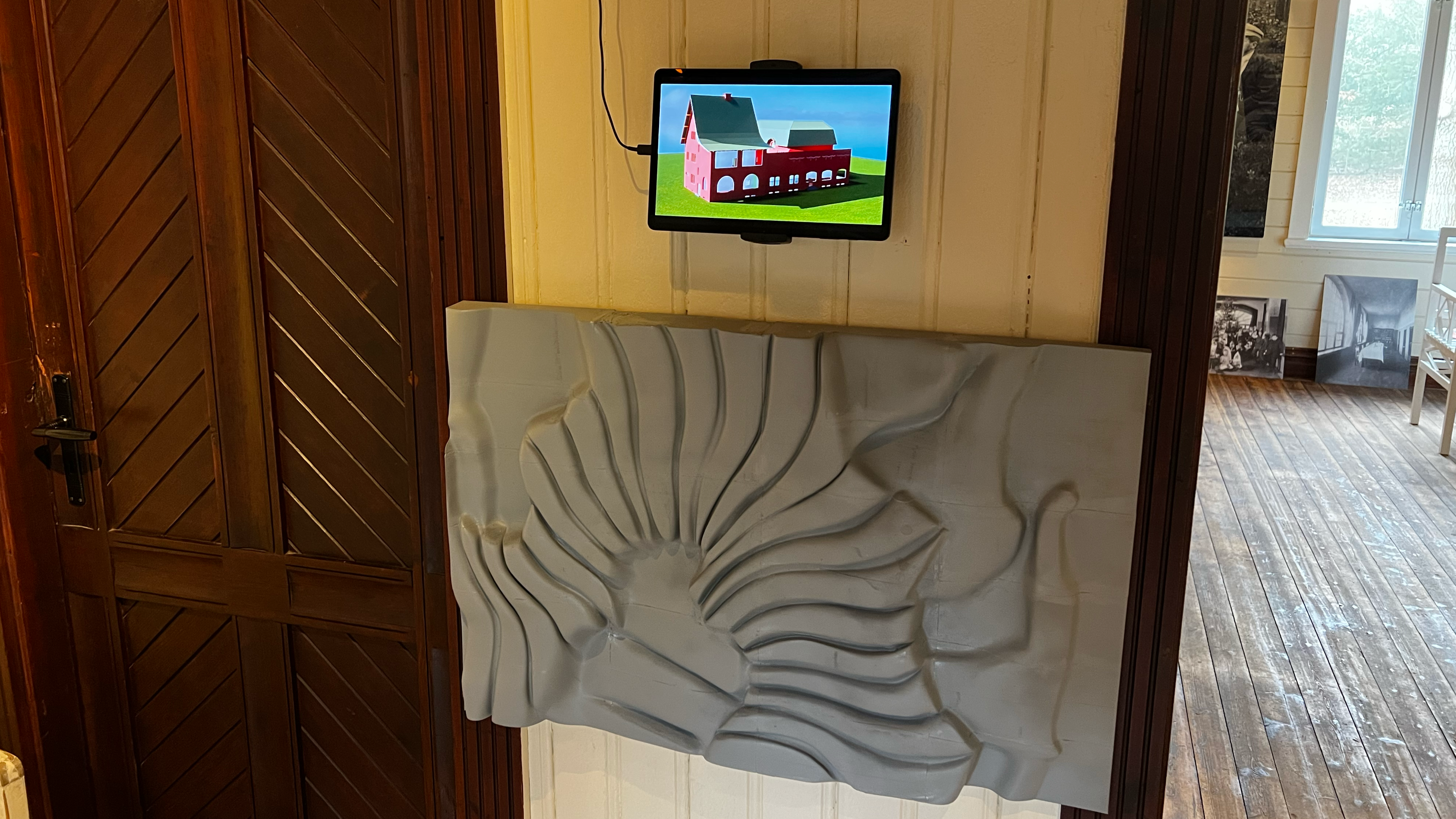 Das nachgebaute Ornamentrelief in der Ausstellung, darüber ein Tablet mit dem Animationsfilm